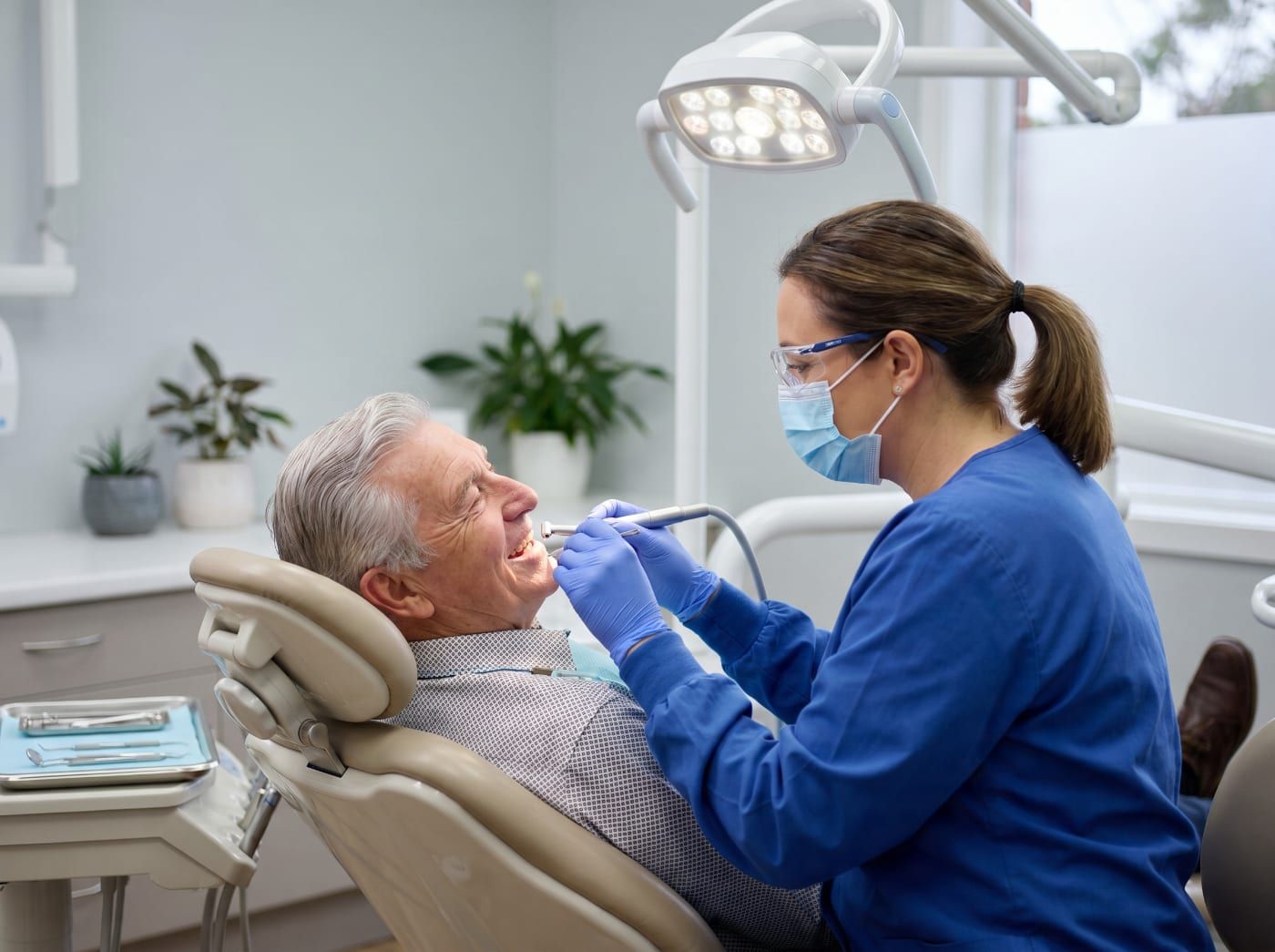 A dentist treating an older patient in a clinic chair