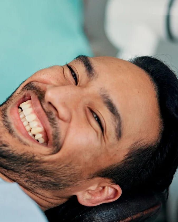 A man smiling in a dental chair after treatment