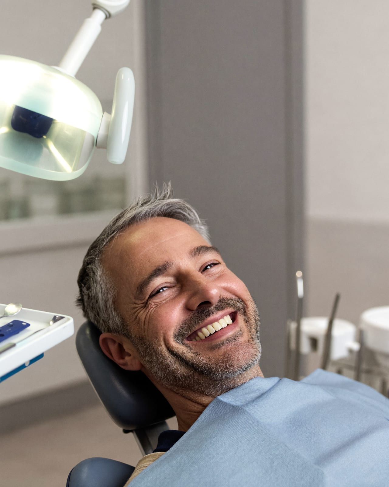 A man smiling in a dental chair on the day of his treatment